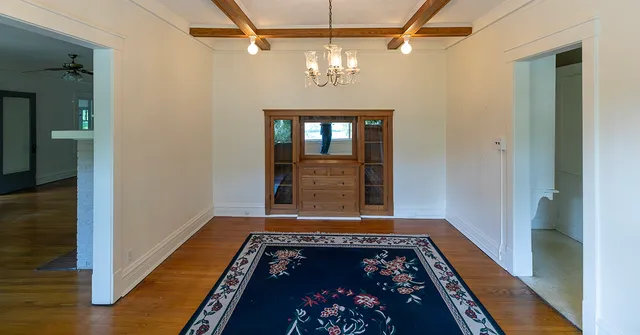 a view of a hallway with wooden floor and a chandelier