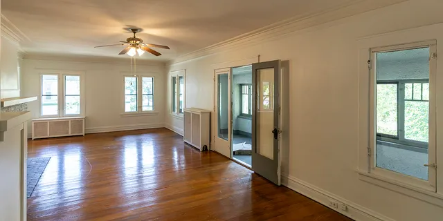 a view of an empty room with wooden floor and a window