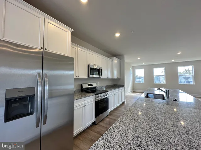 a large kitchen with stainless steel appliances kitchen island granite countertop a refrigerator a sink a stove and white cabinets