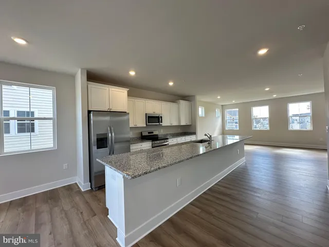 a large kitchen with stainless steel appliances granite countertop a large counter top a stove and a wooden floors