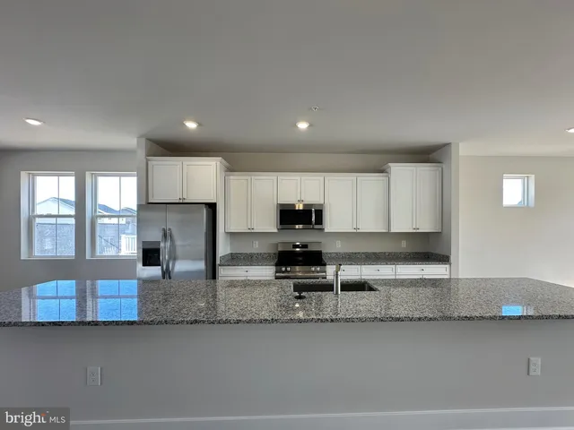 a kitchen with stainless steel appliances granite countertop a sink a stove and a refrigerator