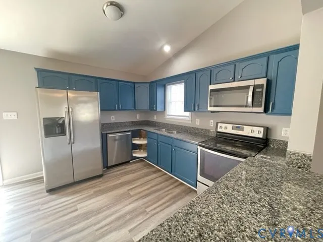 a kitchen with granite countertop a refrigerator stove and microwave