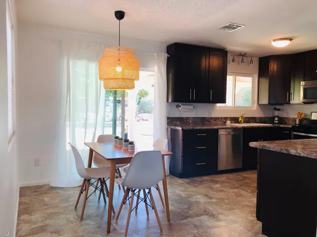 a kitchen with stainless steel appliances granite countertop a stove top oven a sink a dining table and chairs