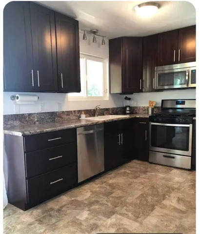 a kitchen with stainless steel appliances granite countertop a sink and a stove