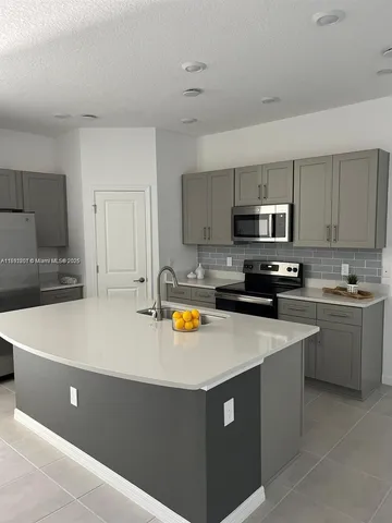 a kitchen with stainless steel appliances a stove a sink a refrigerator a microwave and cabinets