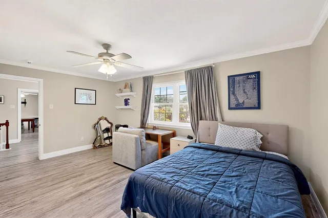 a bedroom with a large bed a chandelier and wooden floor