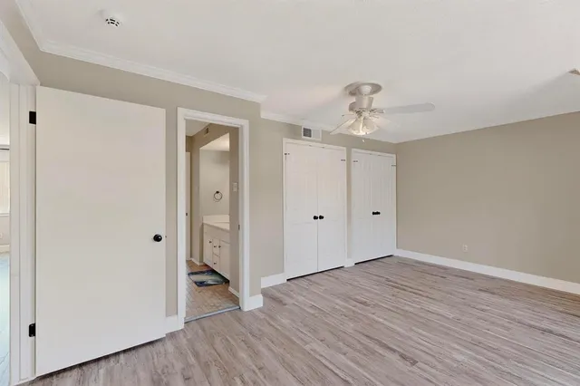 a view of an empty room with wooden floor and closet