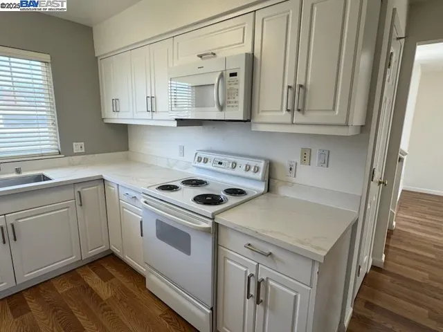 a kitchen with stainless steel appliances granite countertop a sink and dishwasher a stove top oven with white cabinets