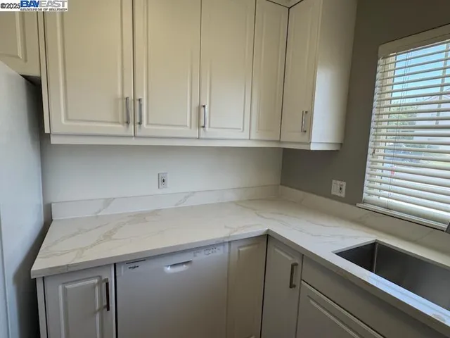 a kitchen with granite countertop white cabinets and a sink