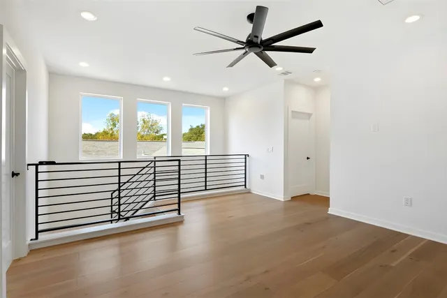 an empty room with wooden floor fan and windows