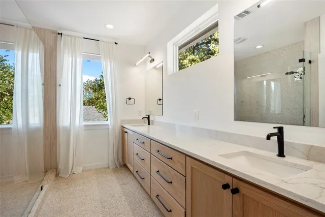 a spacious bathroom with a double vanity sink a large mirror a shower and a bathtub