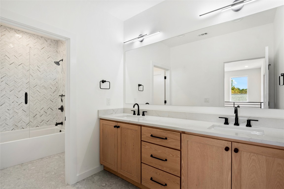 18205 Fair Lane Jonestown, TX 78645 - Photo 29 of 40 a bathroom with a granite countertop sink a toilet a mirror and shower