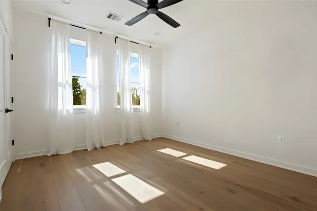 an empty room with wooden floor and windows