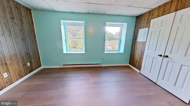 an empty room with wooden floor and windows