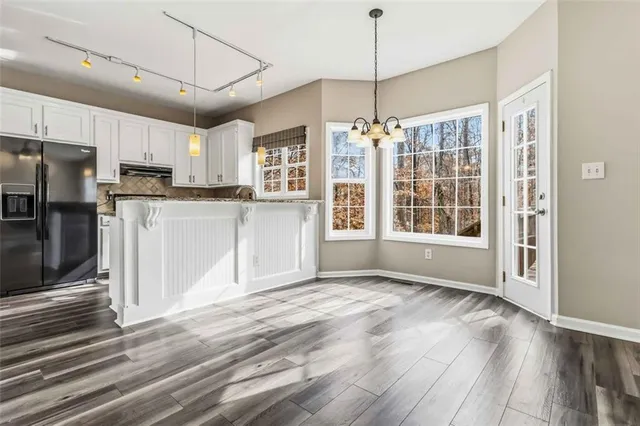 a kitchen with stainless steel appliances granite countertop a stove top oven a refrigerator a sink and white cabinets