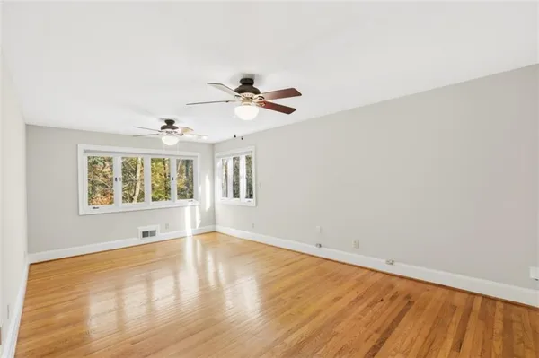 an empty room with wooden floor and windows