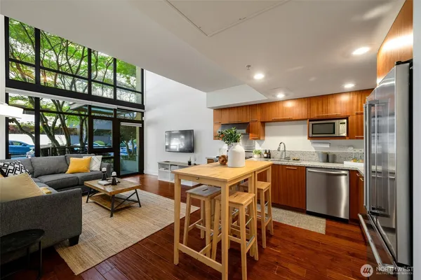 a kitchen with stainless steel appliances granite countertop a stove a refrigerator a kitchen island a table and chairs with wooden floor