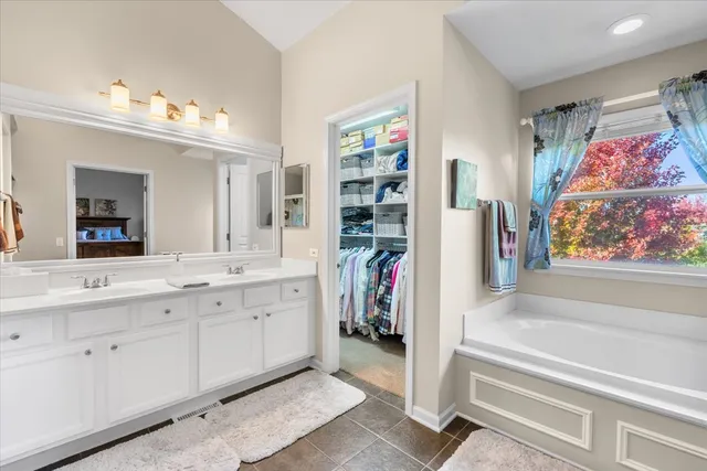 a spacious bathroom with a double vanity sink a mirror and a bathtub