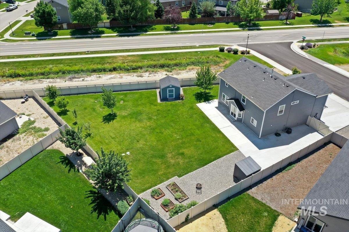 12310 West Hidden Point Drive Star, ID 83669 - Photo 34 of 48 Spacious property featuring a large green lawn, a dedicated garden area with planters, and 2 separate storage sheds