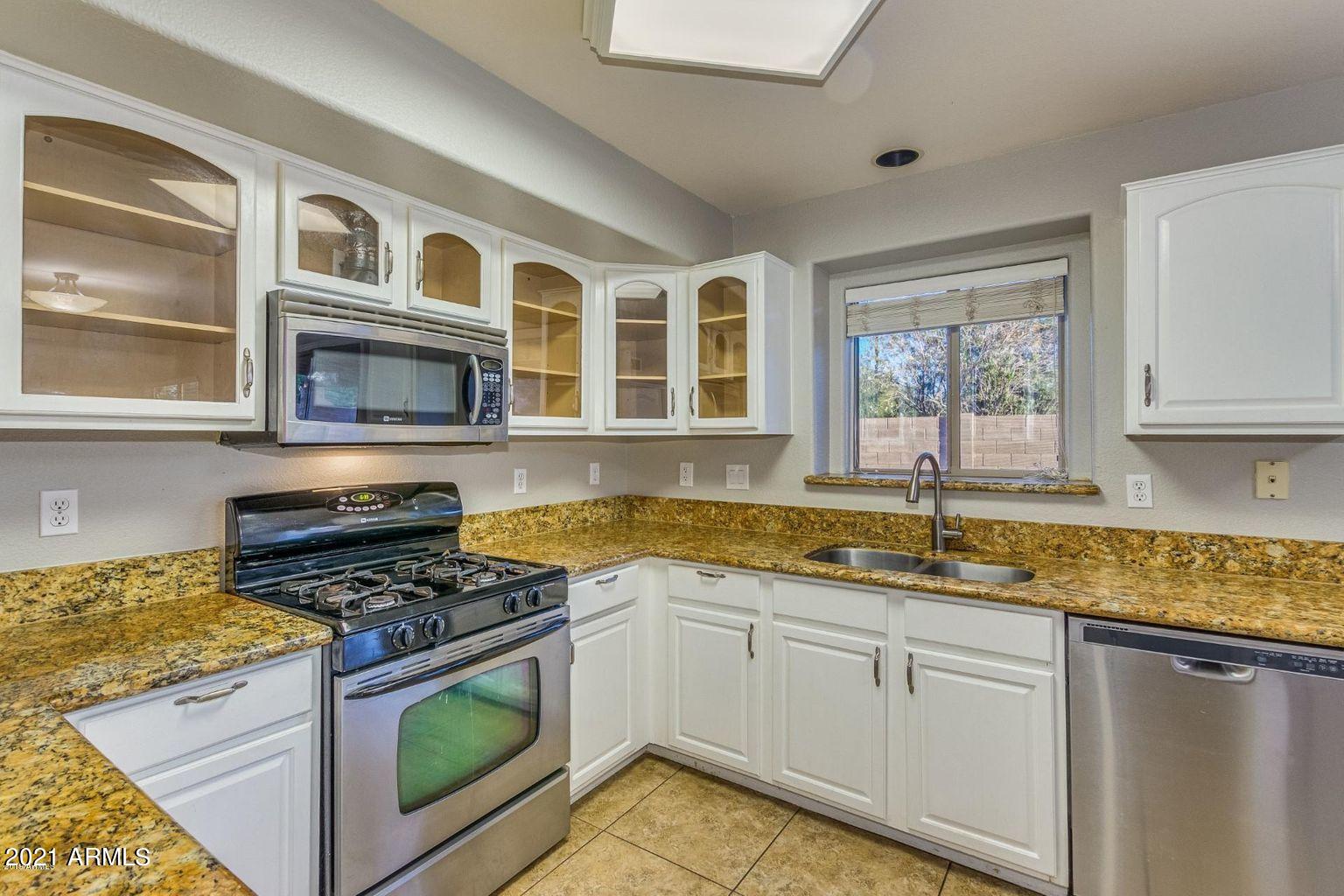 1791 East Del Rio Street Gilbert, AZ 85295 - Photo 8 of 28 a kitchen with granite countertop stainless steel appliances a stove sink and microwave