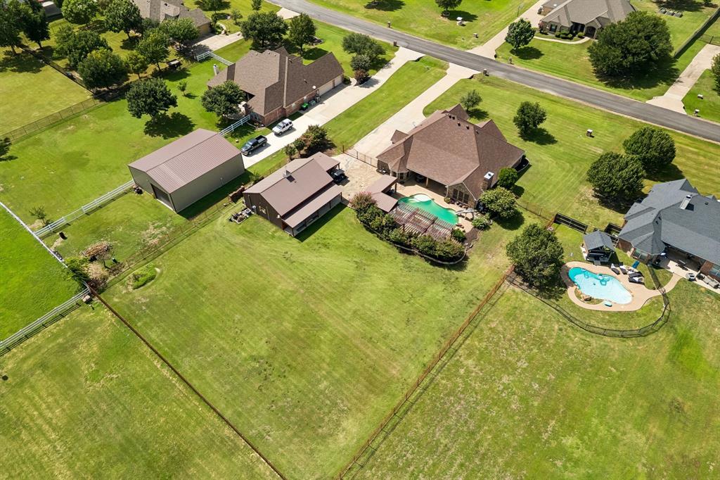 317 Singing Quail Trail Haslet, TX 76052 - Photo 3 of 32 Expansive property featuring a main residence, a secondary structure with a porch, a large detached outbuilding, and a fenced swimming pool