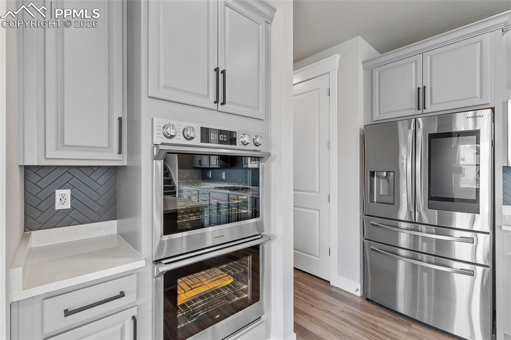 15777 Little Bluestem Road Monument, CO 80132 - Photo 6 of 50 a kitchen with stainless steel appliances white cabinets and wooden floors