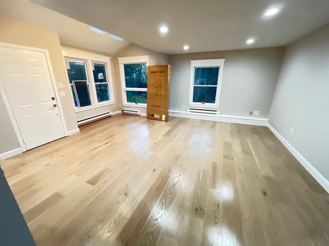 an empty room with wooden floor and window