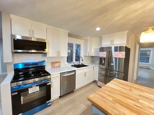 a large kitchen with stainless steel appliances granite countertop a stove a sink and a microwave