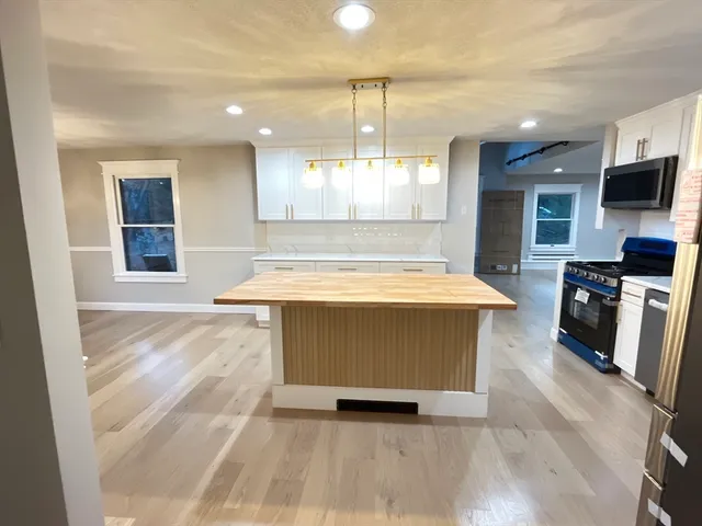 a large white kitchen with kitchen island a stove a refrigerator a sink and a counter top space