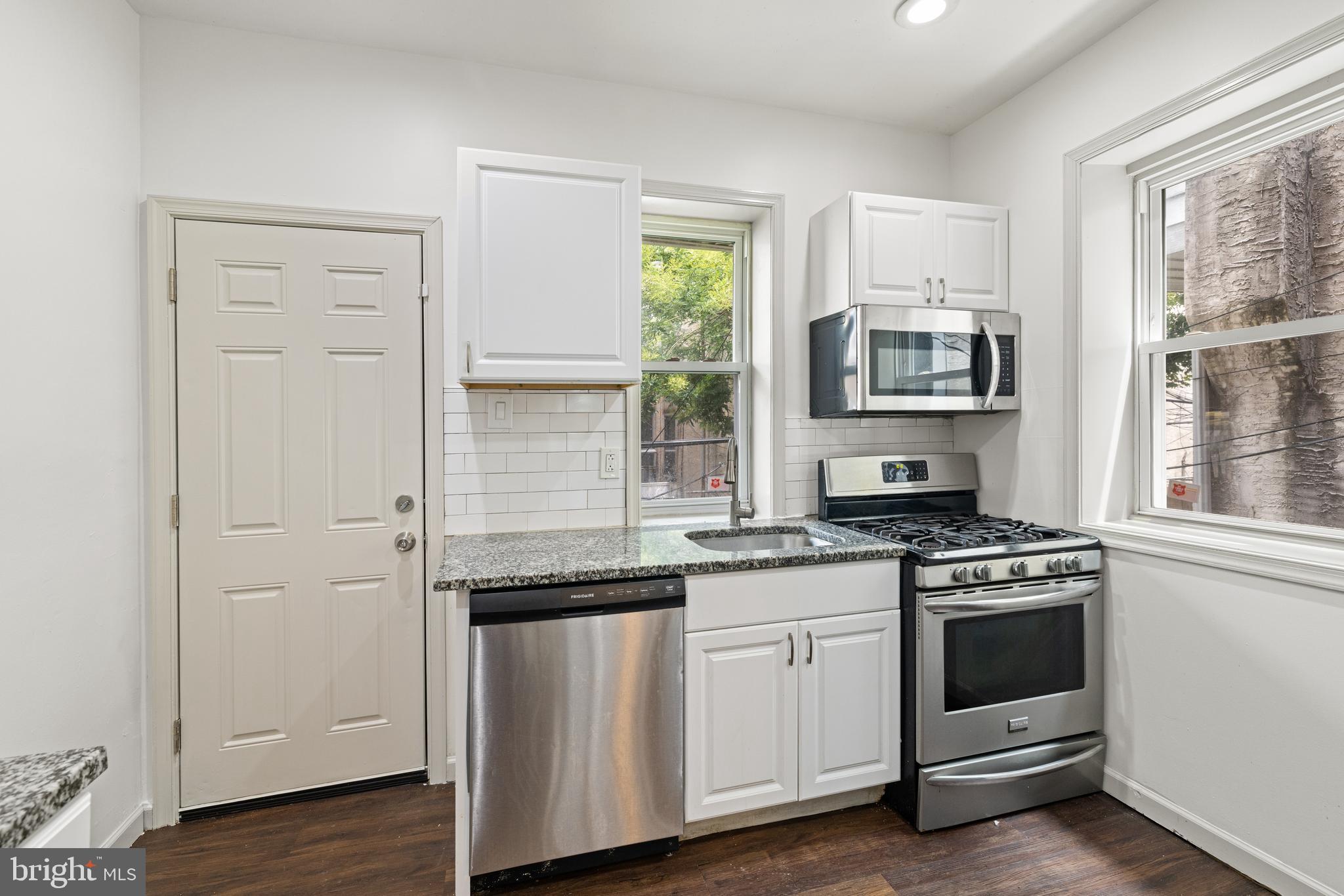 5551 Addison Street Philadelphia, PA 19143 - Photo 11 of 21 a kitchen with cabinets appliances a sink and a window