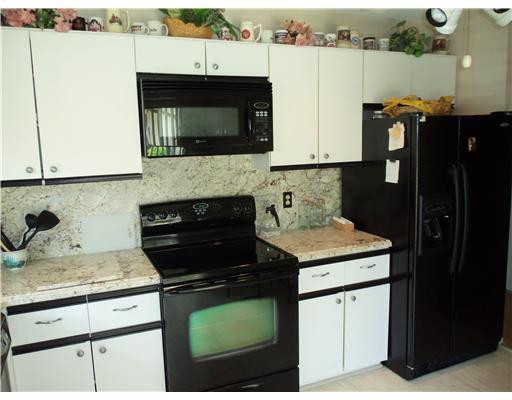 20973 Boca Ridge Drive West Boca Raton, FL 33428 - Photo 3 of 16 a kitchen with granite countertop white cabinets and black appliances