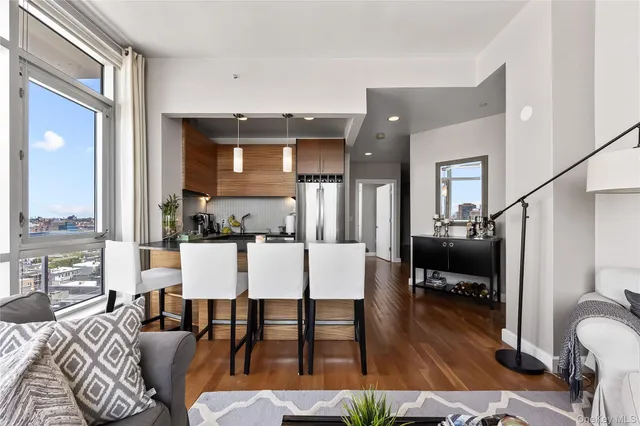a living room with furniture kitchen view and a wooden floor