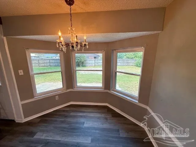 a view of a room with wooden floor chandelier and windows