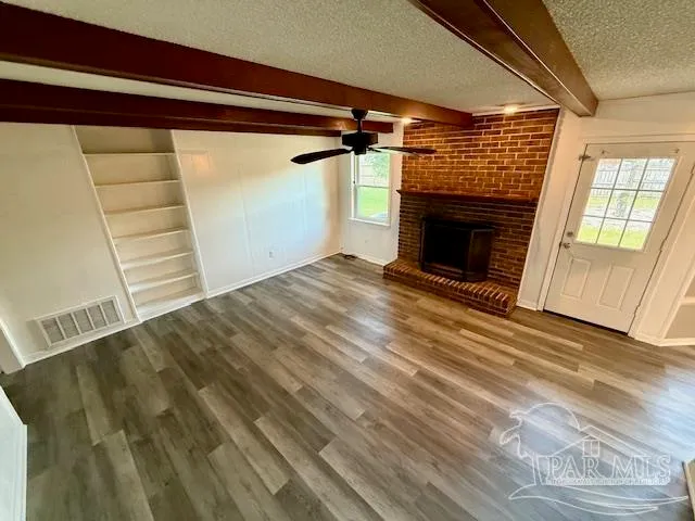 a view of empty room with wooden floor and fireplace