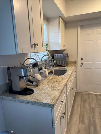 a kitchen with white cabinets and sink