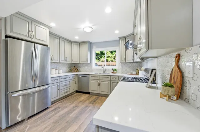 a kitchen with a refrigerator a sink dishwasher a stove and white cabinets with wooden floor