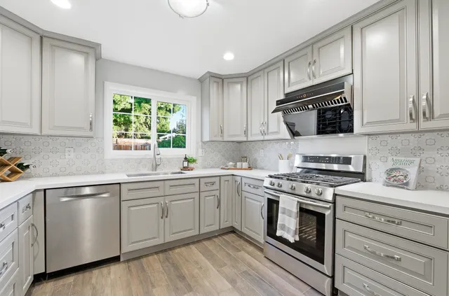 a kitchen with cabinets stainless steel appliances and wooden floor