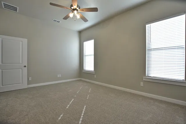 an empty room with windows and fan
