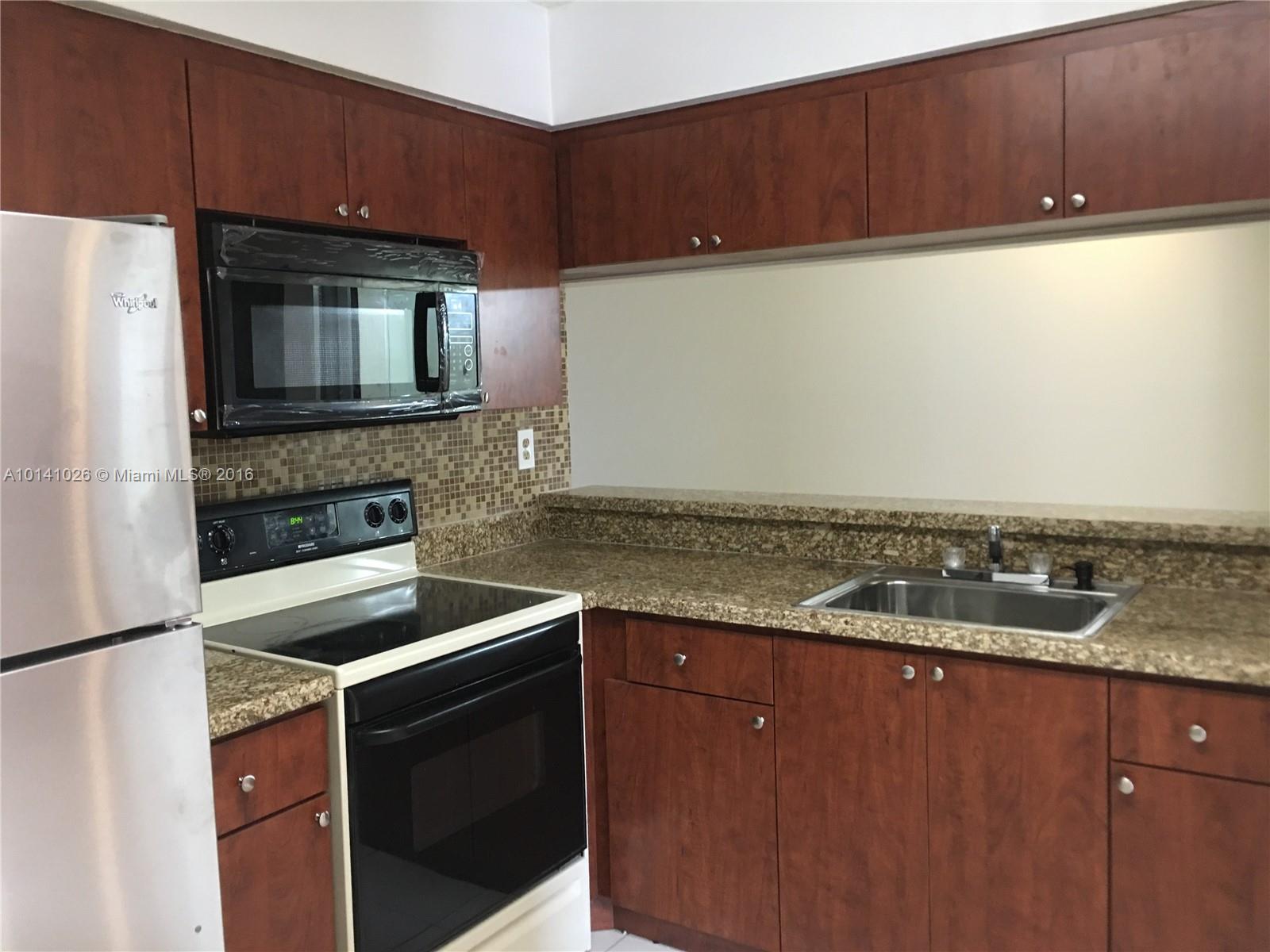 13946 Southwest 90th Terrace, Unit 13946 Miami, FL 33186 - Photo 11 of 16 a kitchen with granite countertop cabinets stainless steel appliances and a counter space