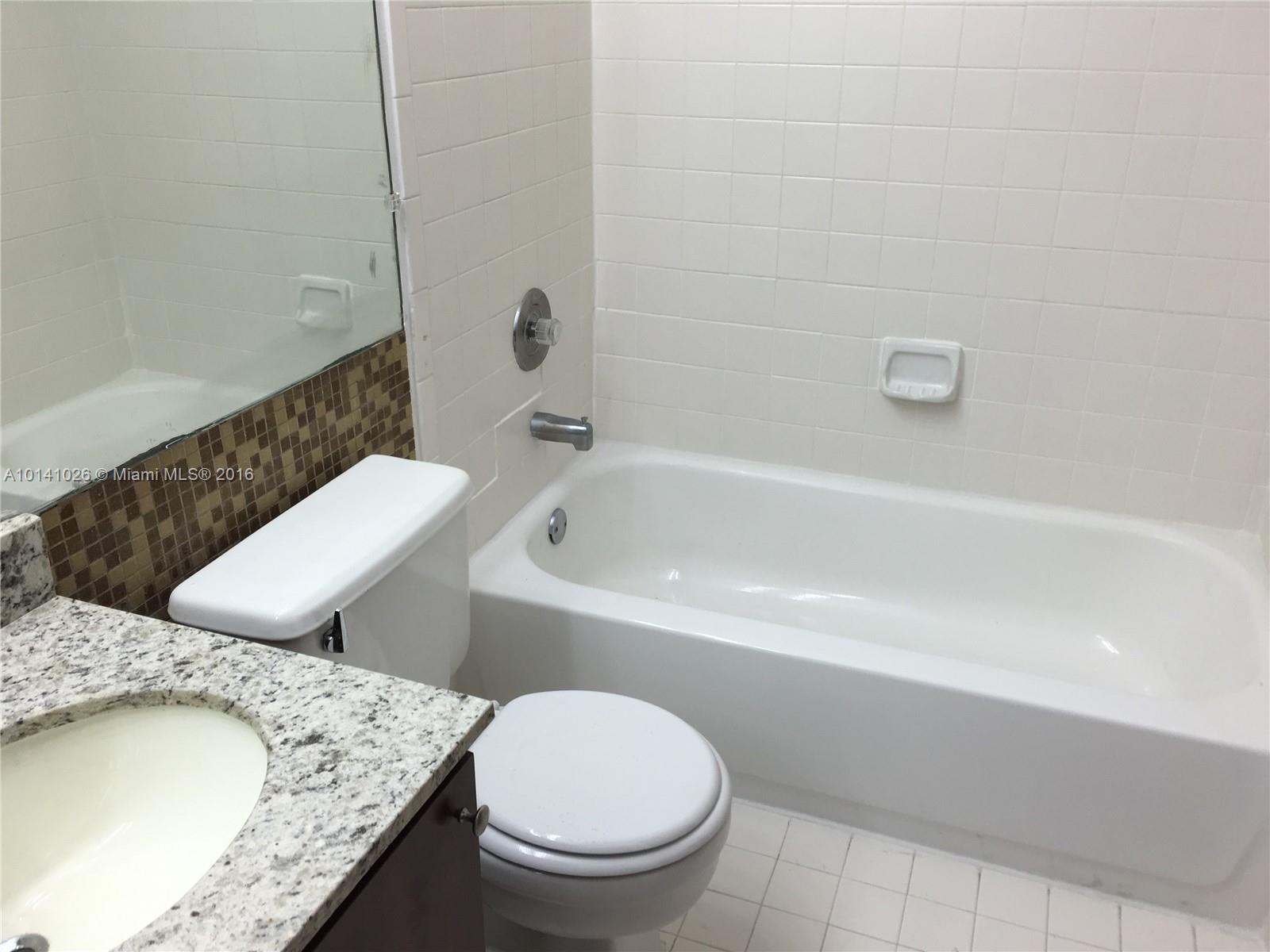 13946 Southwest 90th Terrace, Unit 13946 Miami, FL 33186 - Photo 9 of 16 a bathroom with a granite countertop toilet a sink and bathtub