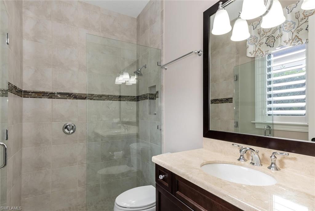 2220 Residence Circle Naples, FL 34105 - Photo 27 of 30 a bathroom with a granite countertop sink toilet a mirror and shower