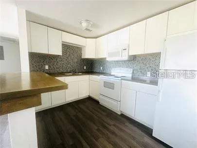 a kitchen with granite countertop a sink a stove and cabinets