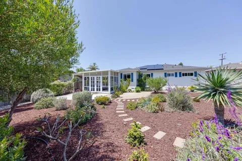 a front view of a house with a yard and potted plants