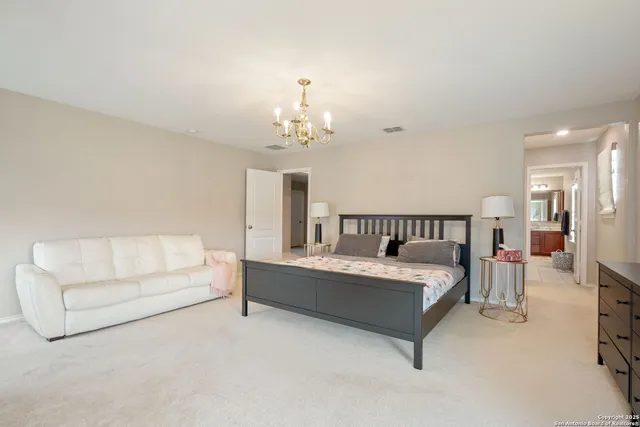 a spacious bedroom with a bed and a chandelier