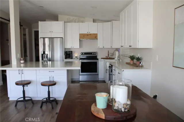 a kitchen with stainless steel appliances granite countertop a refrigerator a stove a sink and white cabinets