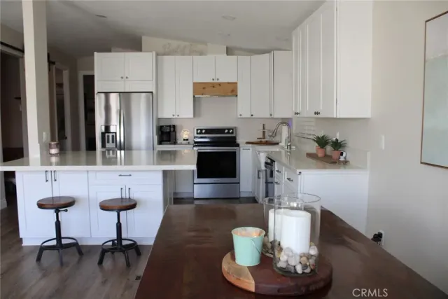 a kitchen with stainless steel appliances granite countertop a refrigerator a stove a sink and white cabinets