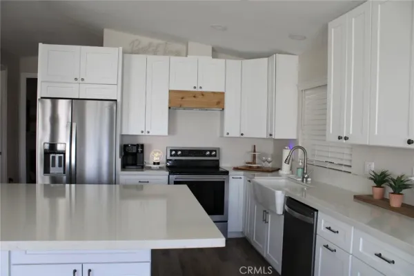 a kitchen with granite countertop a refrigerator sink and white cabinets