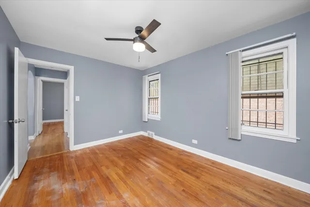 a view of empty room with wooden floor and fan