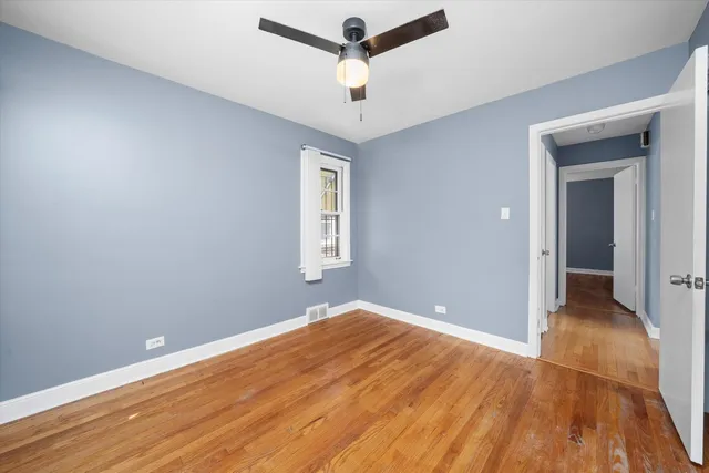 a view of empty room with wooden floor and ceiling fan
