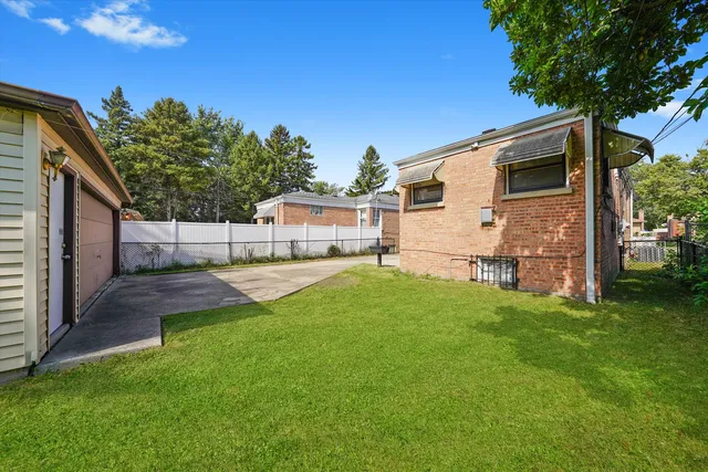 a view of a backyard with a large tree and wooden fence